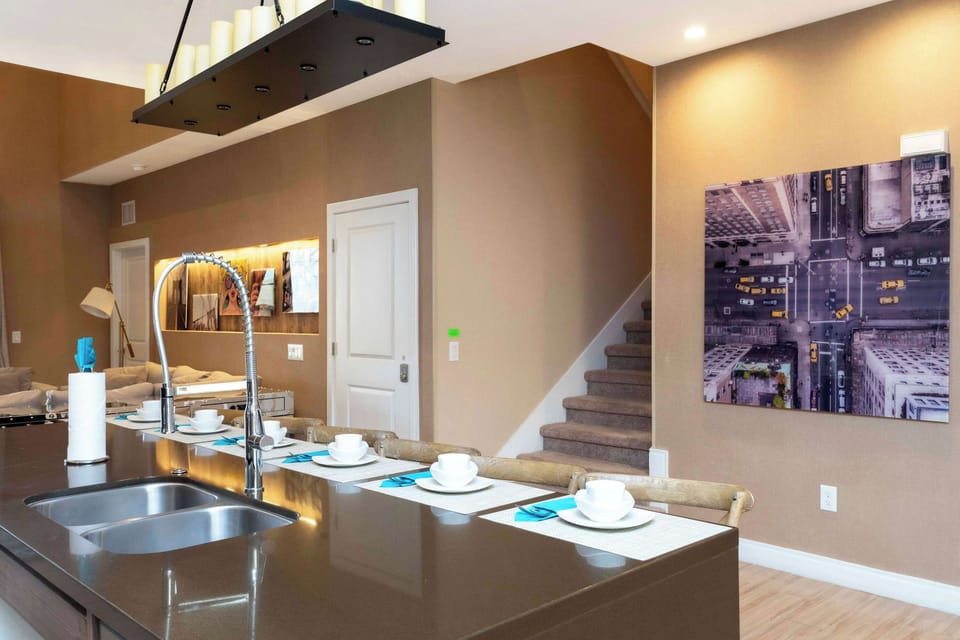 Sleek kitchen island with quartz-style countertop, pull-down faucet, and bar seating for 4 beneath a candle-style chandelier-warm, contemporary feel.