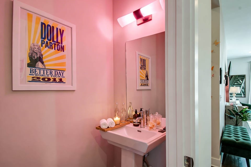 This half bath is pure Dolly: pink walls, a Dolly Parton poster, and the kind of decor that turns a quick stop into a photo moment
