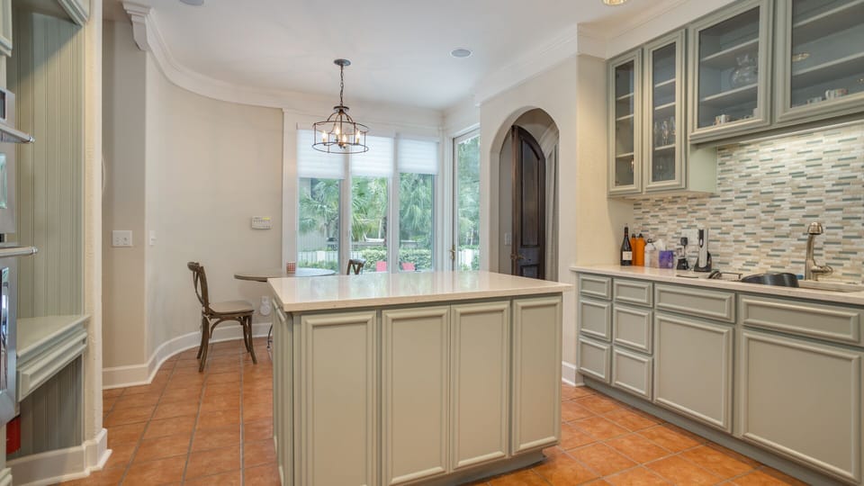 This inviting kitchen features custom cabinetry in a soft coastal palette, quartz countertops, and a spacious center island.