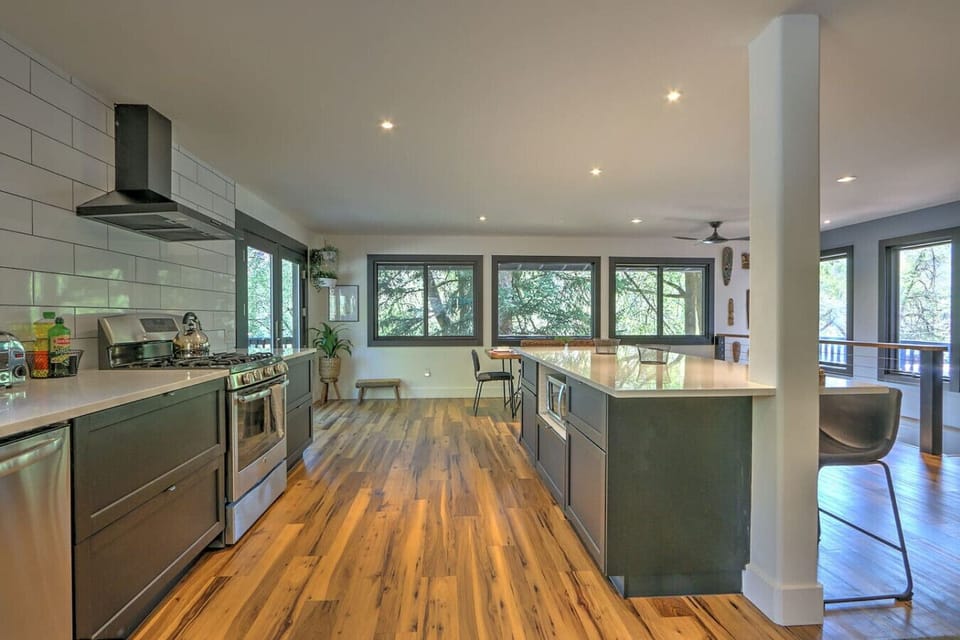 Open concept chef`s kitchen with large windows overlooking trees & deck