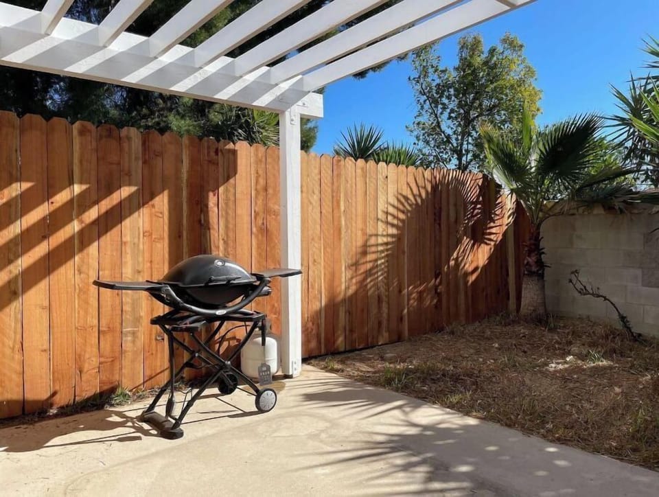Patio with Adirondack chairs, small table and Weber barbecue.