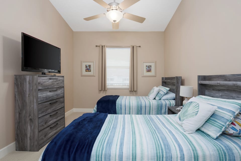 3rd Bedroom showcases 2 Twin Beds with Beach Blue Hues and TV.