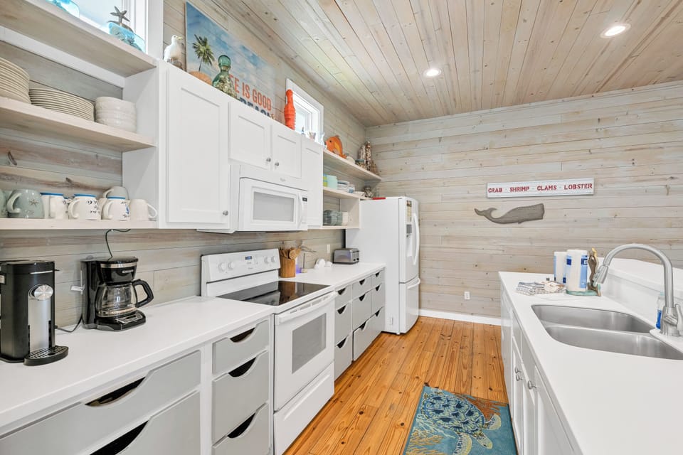 Your charming coastal kitchen awaits with warm wood details, modern appliances, and nautical touches for memorable meal preparation.