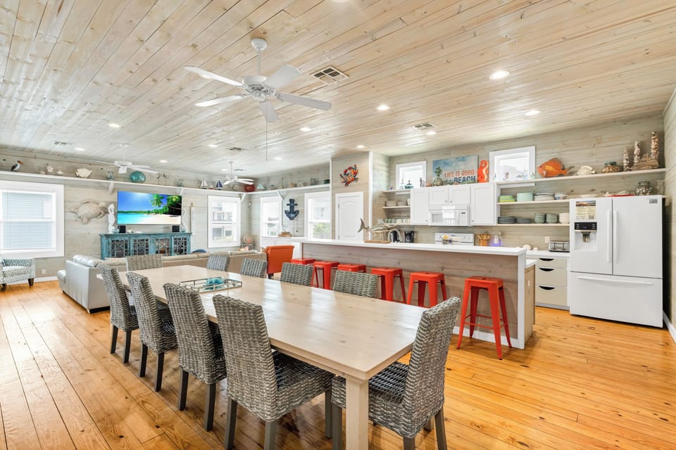 Gather around your spacious dining table with coastal charm, where warm wood tones and beach-inspired decor create perfect moments together.