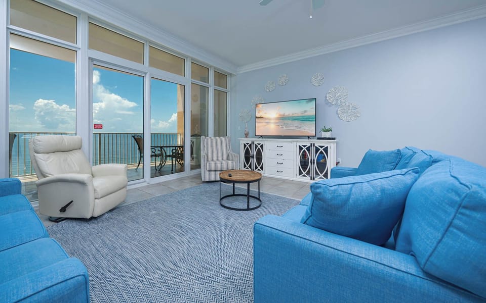 Relax in the airy living room, featuring plush seating and a large TV, with stunning views just beyond the glass doors