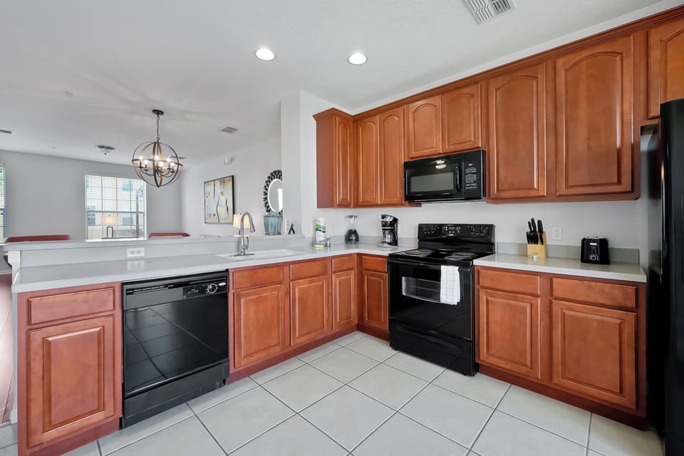 Your fully equipped kitchen features warm wood cabinets, granite countertops, and modern black appliances—perfect for preparing memorable meals during your stay.