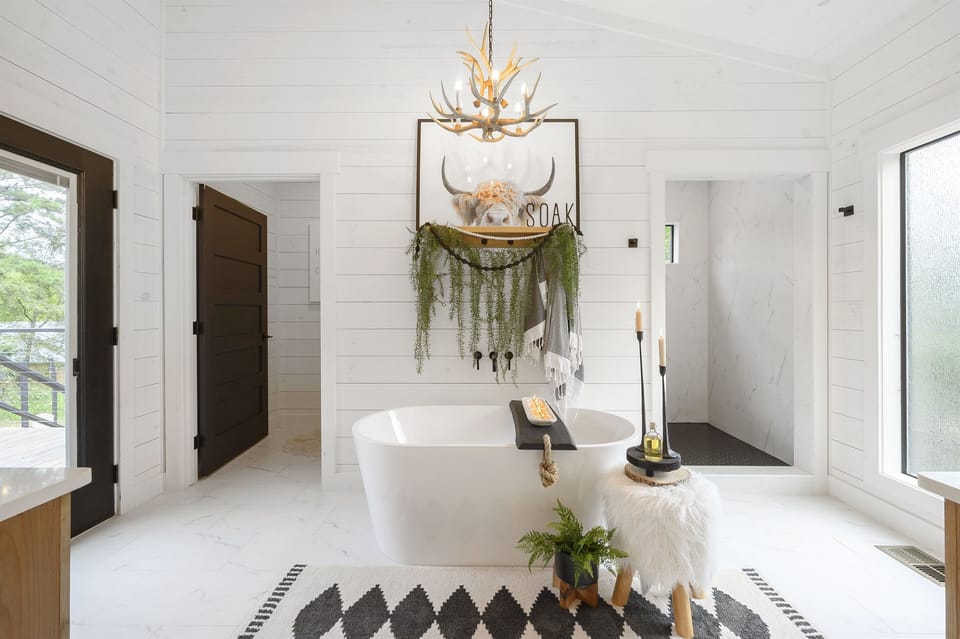 A luxurious master bathroom featuring an oversized soaking tub, perfect for unwinding after a long day. The modern chandelier and rustic decor enhance the spa-like feel.