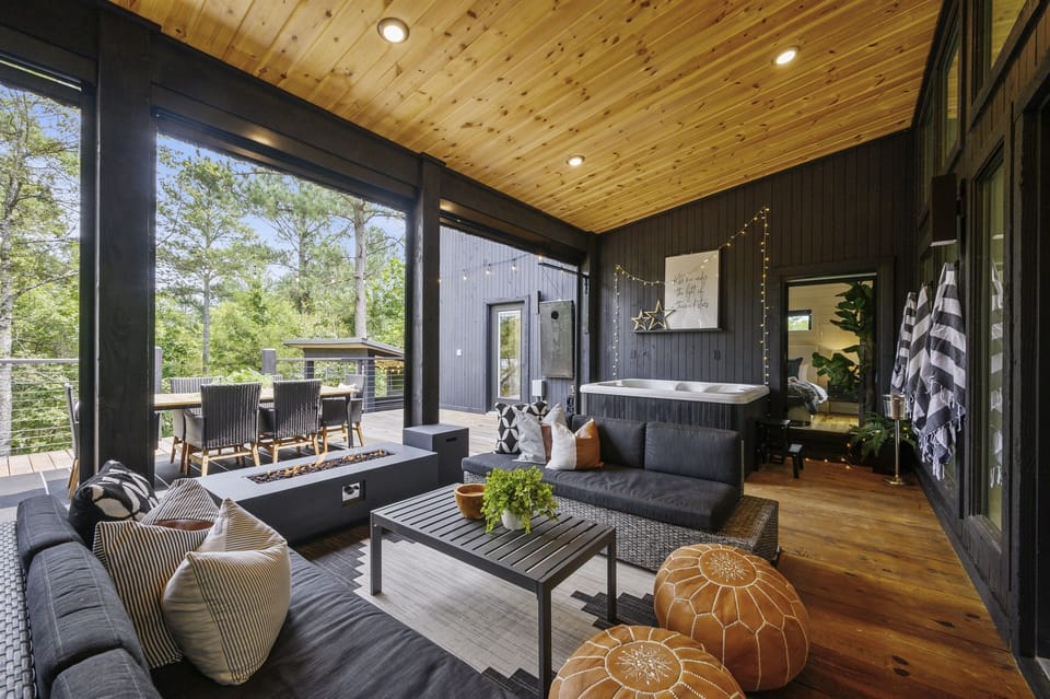 Experience luxury outdoor living with a private hot tub, cozy lounge seating, and serene forest views—perfect for relaxing after a day of hiking or exploring Broken Bow