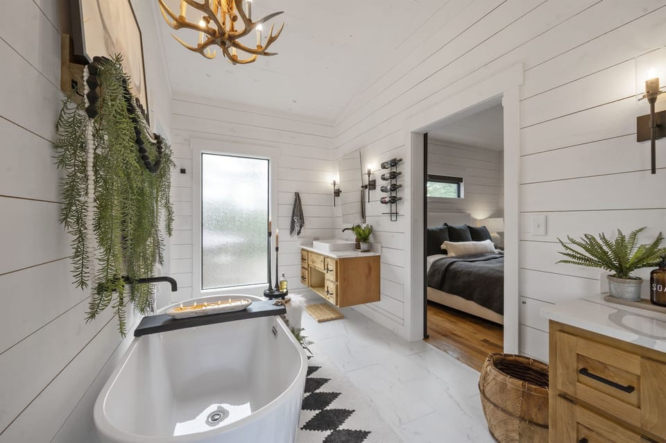 Spacious en-suite bathroom with dual vanities, a soaking tub, and elegant lighting. A mix of modern and rustic elements creates a serene and inviting space.