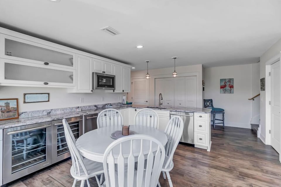- Side beverage fridge and deep drawers add convenience to this coastal kitchen
- Breakfast nook seating and island pendants enhance mealtime flexibility
- Crisp white finishes, wide plank floors, and sunlight create a breezy vibe