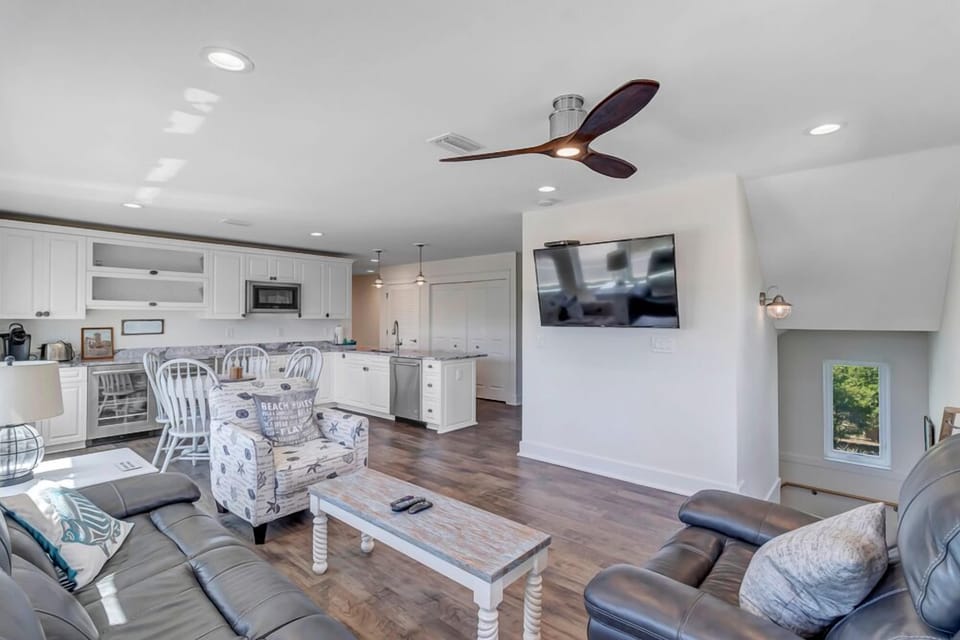 - Wall mounted TV and comfy seating set the stage for laid back movie nights
- Kitchen island and granite counters offer extra prep space and style
- Overhead fan and recessed lighting add comfort to this airy shared zone