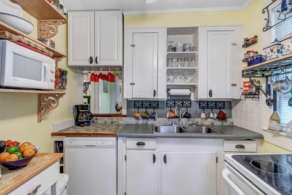 - Cook in this adorable vintage kitchen featuring white cabinetry and open glass storage
- Tile backsplash and quirky accents create a cozy, personalized atmosphere
- Everything you need is within reach for meals and snacks