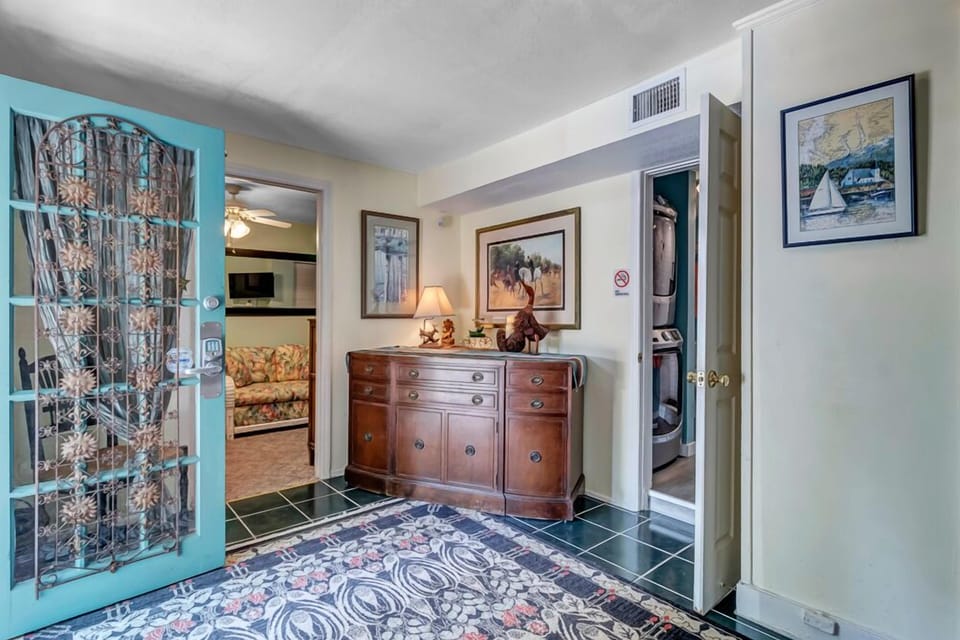 - Enter through a colorful teal door into a warm and welcoming foyer with classic charm
- Wood furnishings and framed artwork create a cozy first impression
- Connects easily to main living spaces and colorful guest rooms beyond
