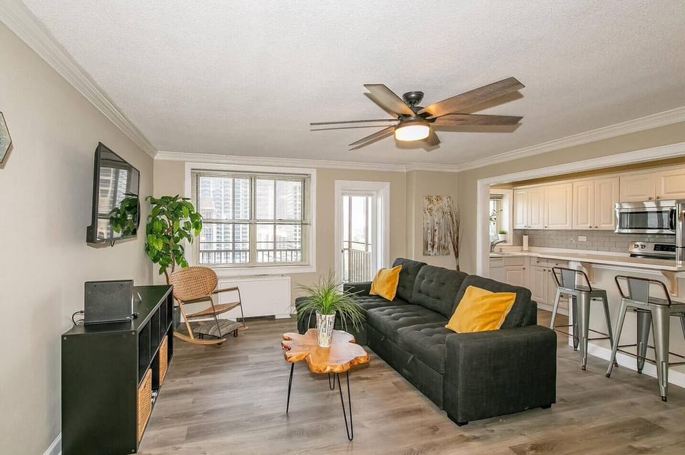 Bright living room w/ cozy sofa, accent pillows & natural light streaming through large windows