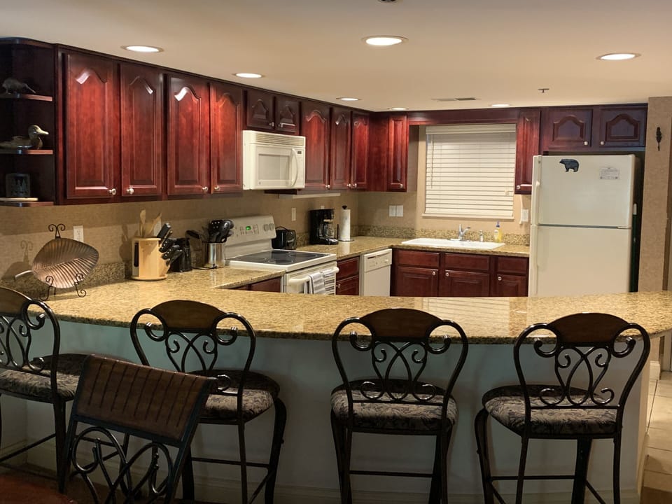 Fully stocked kitchen with granite countertops and cherry cabinets.
