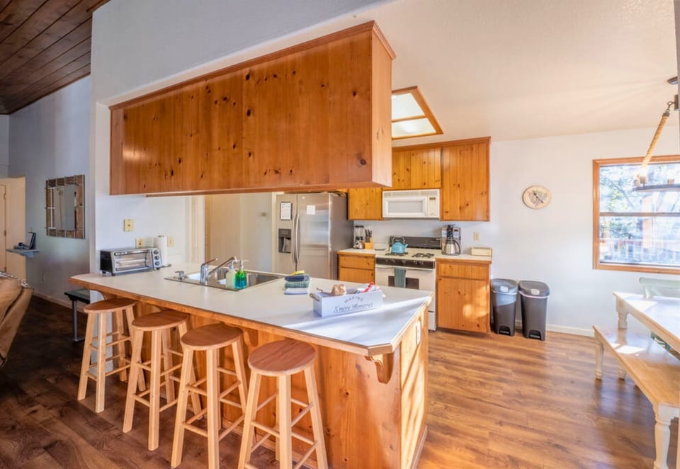 A spacious, wood-finished kitchen with a welcoming breakfast bar offers a perfect spot for morning gatherings in a cabin atmosphere.