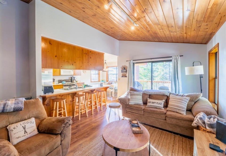 A warm and inviting cabin interior blends open-plan living with rustic coziness and a touch of modern comfort.