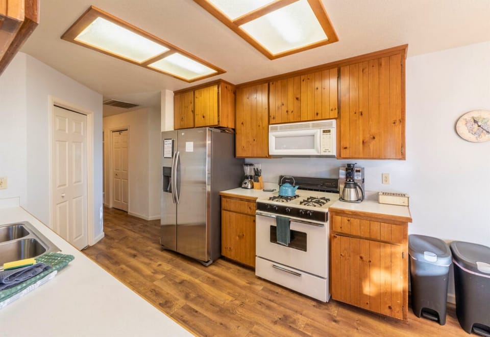 A wood-accented kitchen with modern amenities, illuminated by skylights for a homely cabin cooking experience.