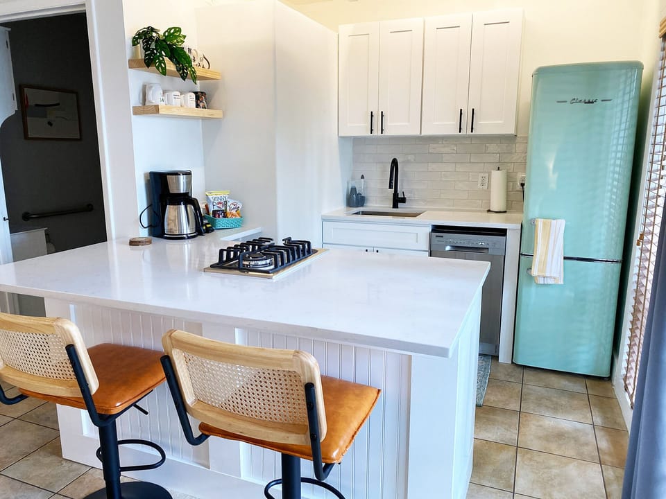 Kitchen with gas cooktop, fridge/freezer, dishwasher, and barstool seating.