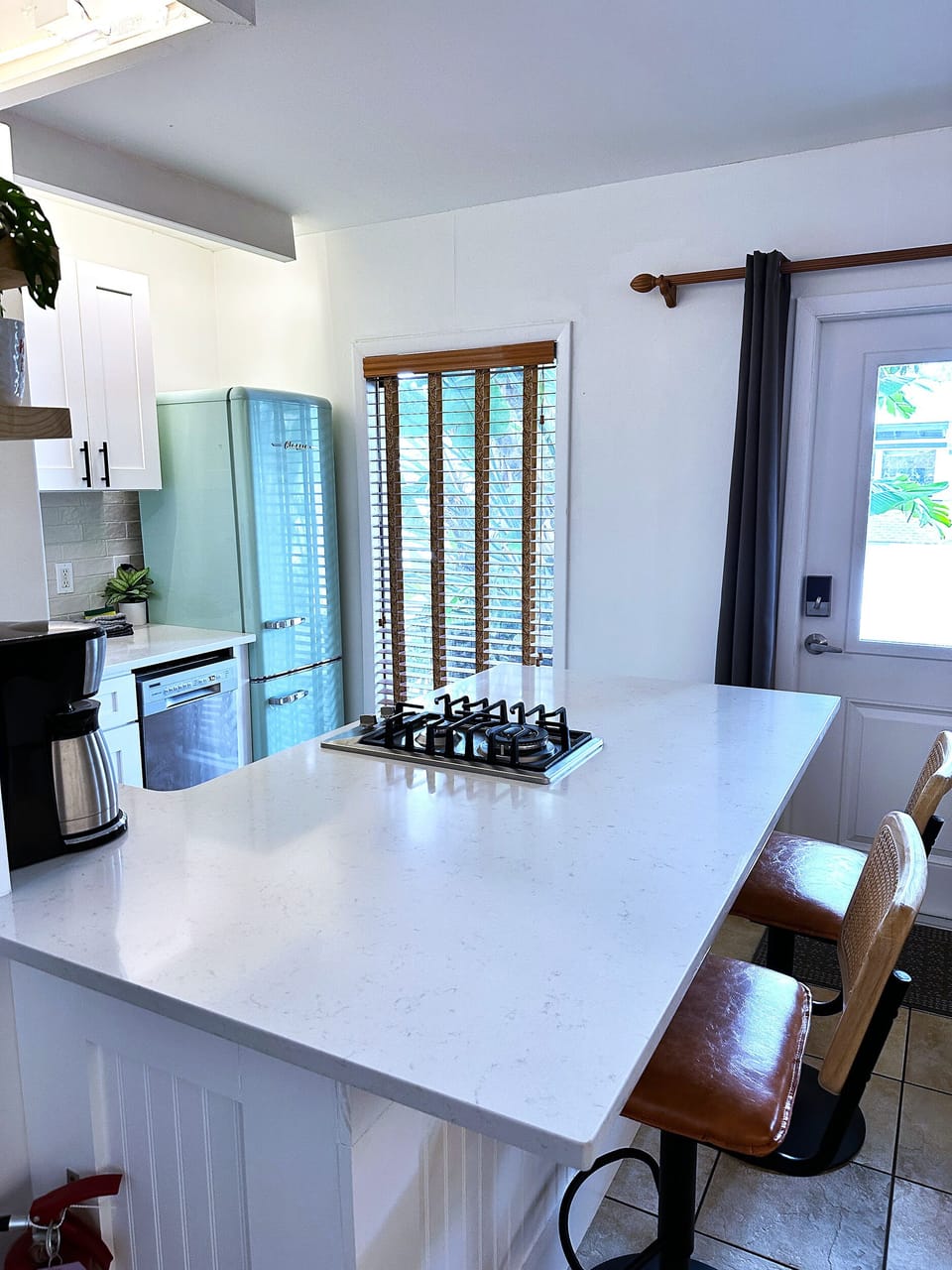 Kitchen with gas cooktop, fridge/freezer, dishwasher, and barstool seating.