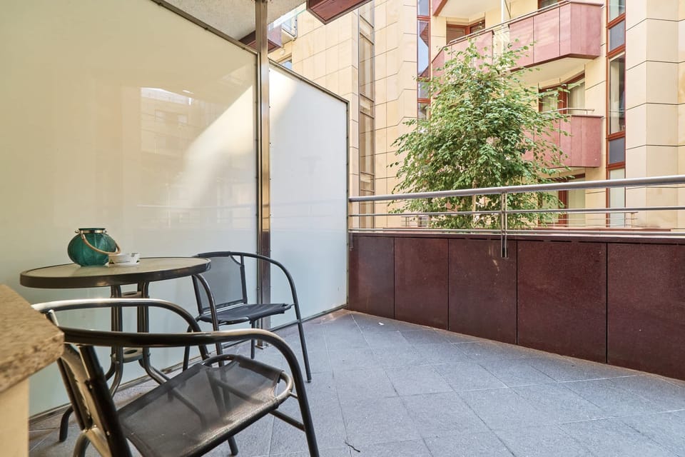 Furnished balcony with green surroundings. 