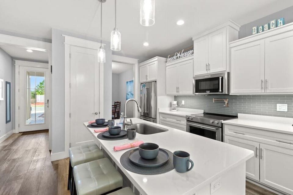 Open fully-stocked kitchen with stainless steel appliances, pot filler, and breakfast bar, located on 1st floor