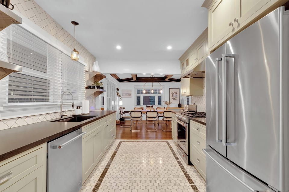 Fully equipped chefs kitchen with shaker-style cabinetry, premium stainless steel KitchenAid appliances, leather-finish granite countertops, Carrera with black marble flooring, and herringbone full wall tiling