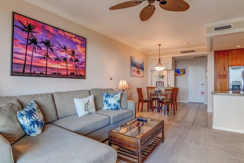     Spacious tropical condo with sunset art, island decor, and dining.