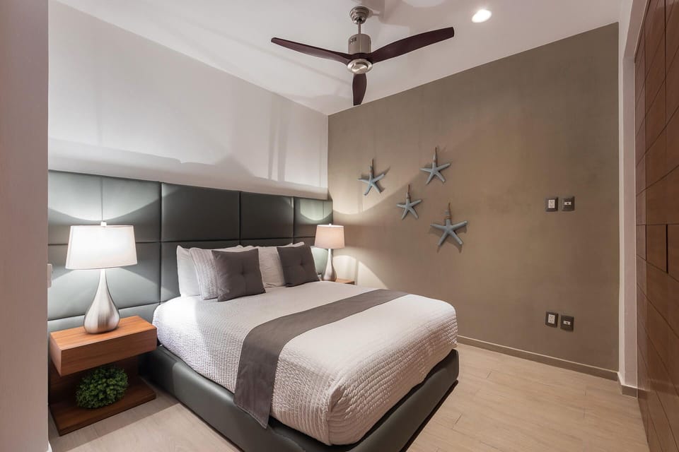 Retreat to a master bedroom oasis centering a plush king-size bed with a dark leather headboard and charming starfish wall decor.