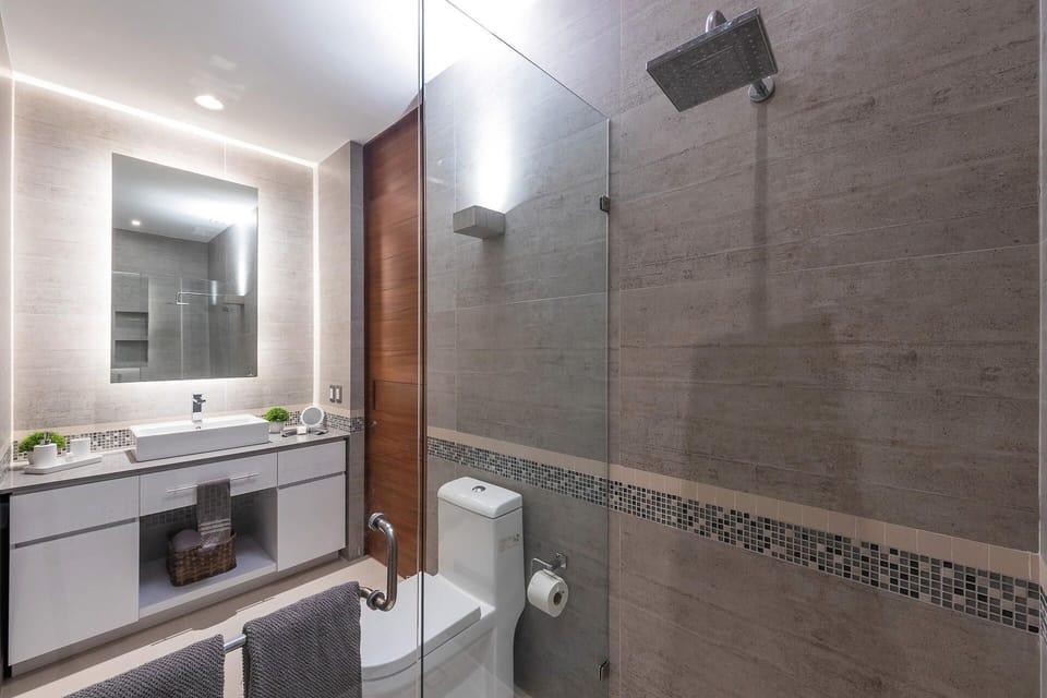 Refresh in a sleek en-suite bathroom detailed with a glass shower enclosure, large-format tile walls, and modern porcelain fixtures.