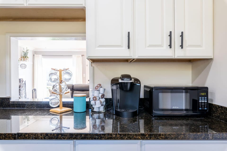 Sleek kitchen corner with microwave, coffee machine, and ample storage