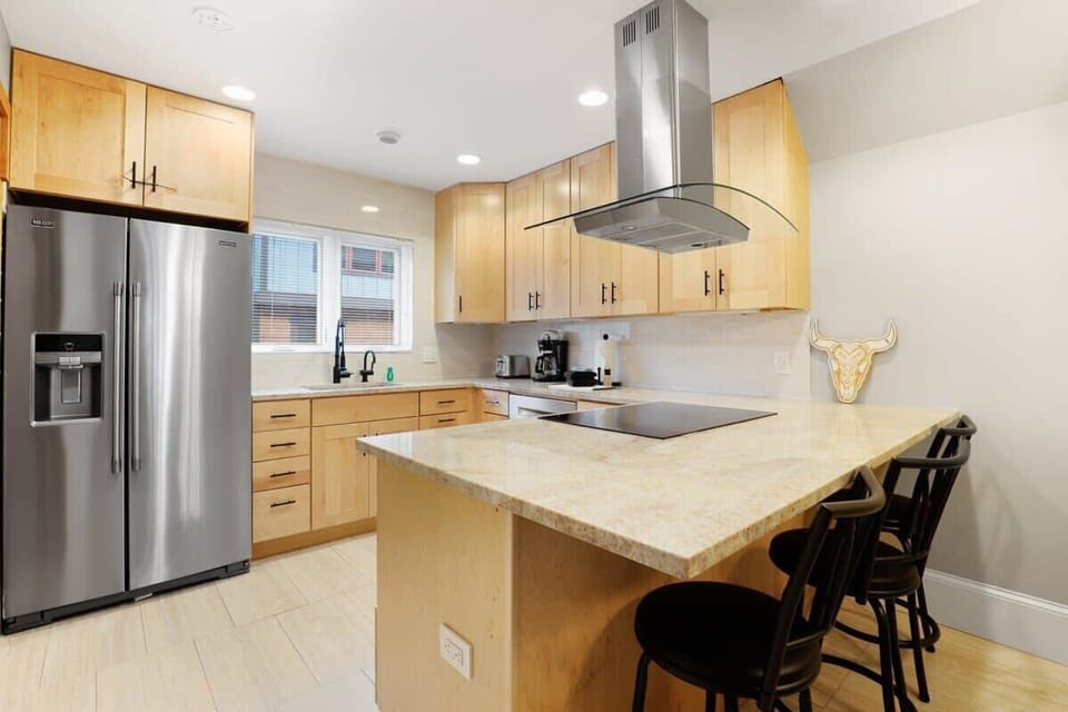 Fully-equipped kitchen with stainless steel appliances and 3 bar stools
