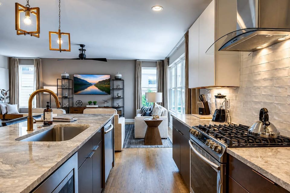 Bright modern kitchen with a marble island and open-concept layout flowing seamlessly into the living room.