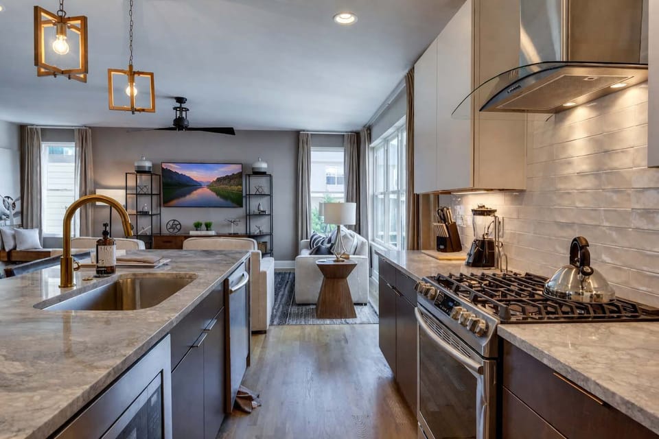 Bright modern kitchen with a marble island and open-concept layout flowing seamlessly into the living room.
