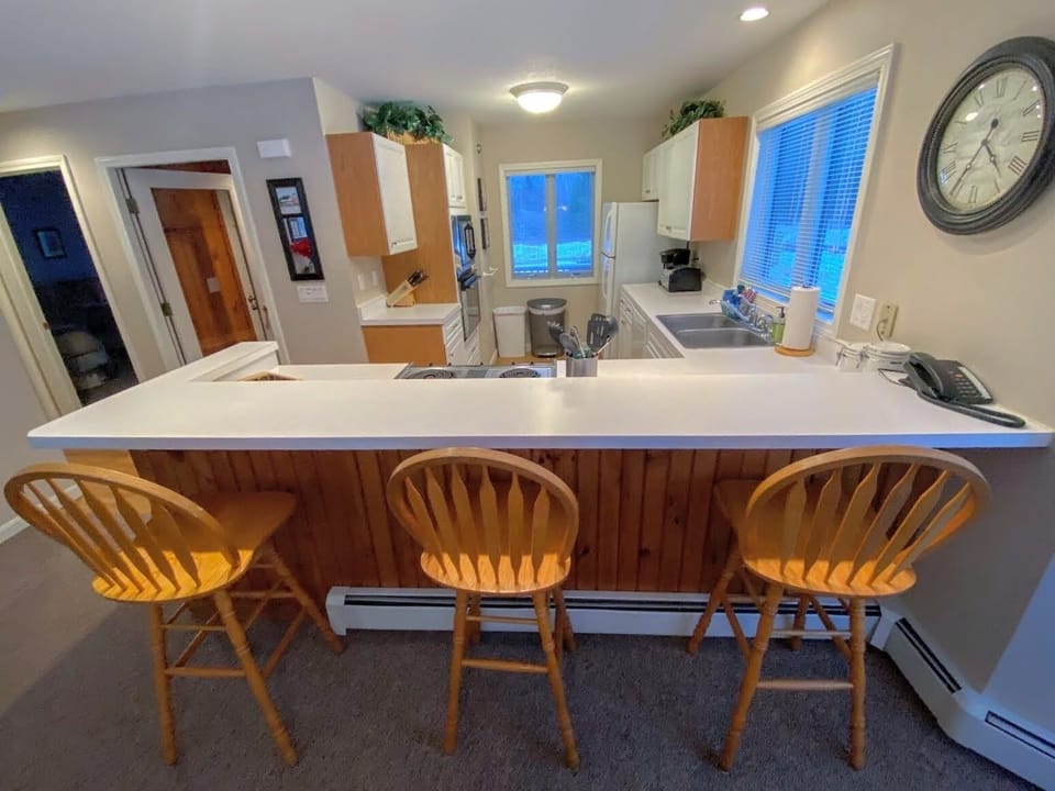 A fully equipped kitchen with a breakfast bar for three