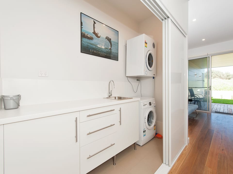 Bright modern laundry room with washer, dryer, sink & storage