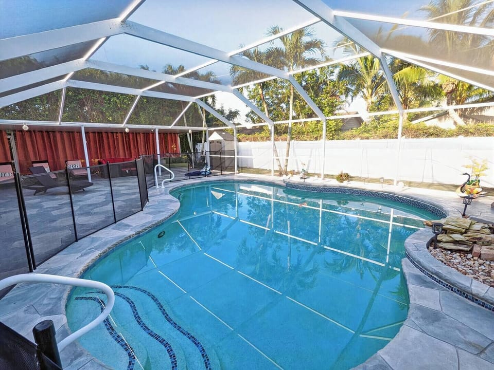 Pool and deck with lanai covering, plenty of seating, and a nice waterfall.