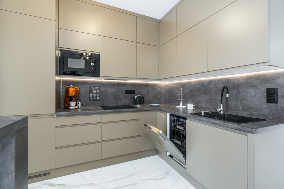 A fully equipped kitchen with beige cabinets, marble countertops, and modern appliances.
