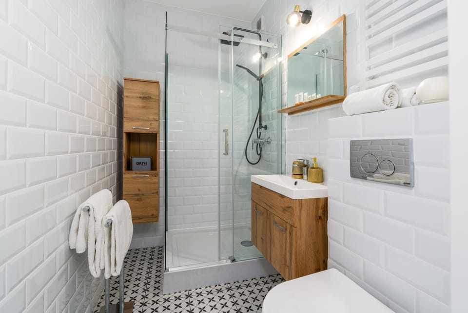 A stylish bathroom with white subway tiles, a walk-in shower, and wood accents for a modern look.
