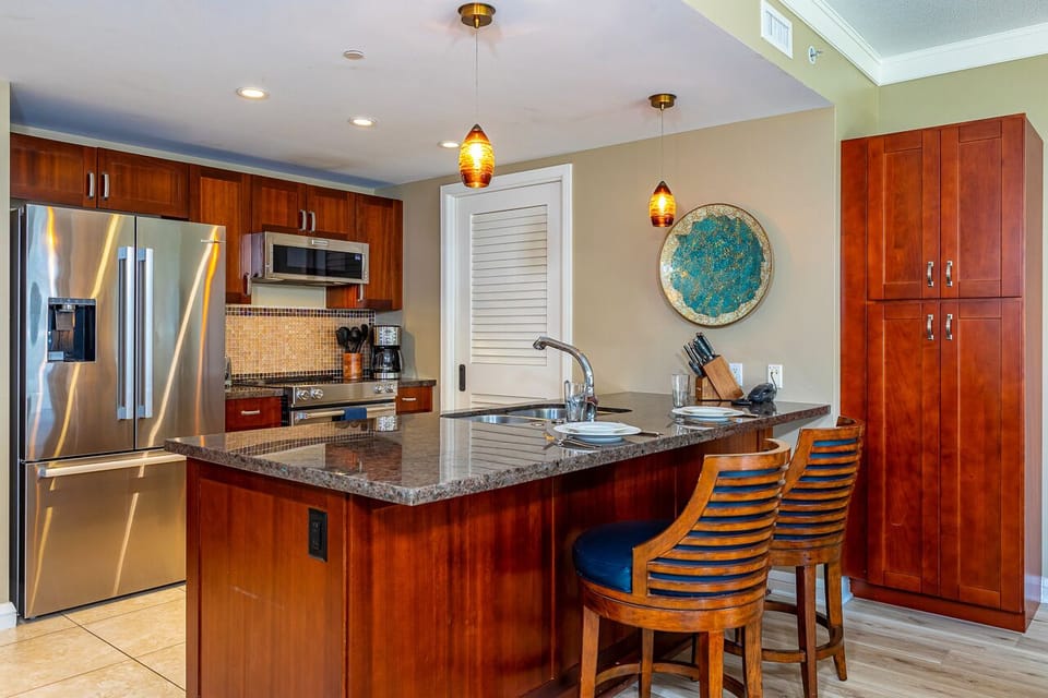 Step into your fully equipped kitchen with warm cherry cabinetry, granite countertops, and modern stainless appliances. The island seating makes meal prep feel effortless and relaxed.