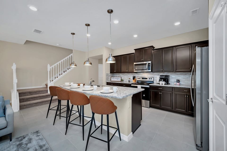 Spacious kitchen of the townhouse in Polk County, Florida - Contemporary open concept Kitchen with countertop and high chairs - Fully equipped with modern appliances - Selectively chosen lighting fixtures that bring both functionality and charm