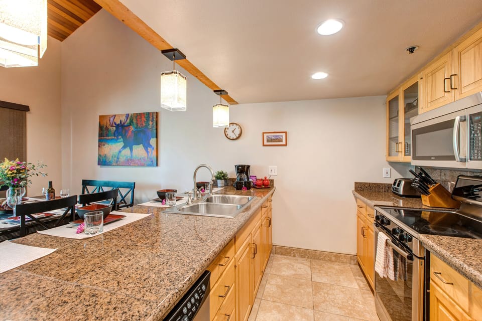 Fully Equipped Kitchen with stone countertops, stainless steel appliances, and bar seating for four