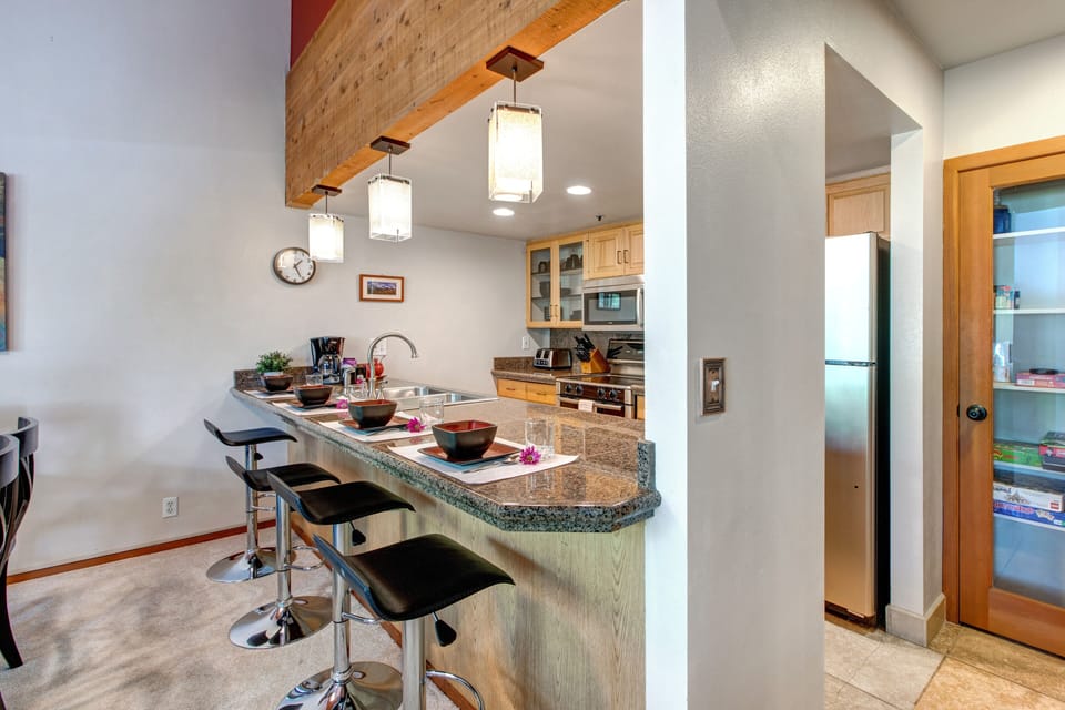 Fully Equipped Kitchen with stone countertops, stainless steel appliances, and bar seating for four