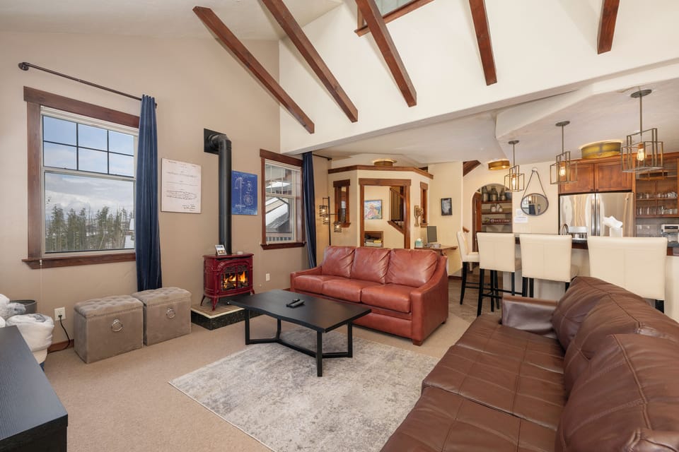 - Cozy living room with leather sofas and wood-beam ceiling   - Warm up by the fireplace after skiing or mountain adventures   - Open layout connects to kitchen and dining for easy gathering