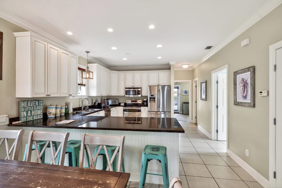 Spacious, beach-inspired kitchen with granite countertops, ample seating, and a bright open layout perfect for gathering.