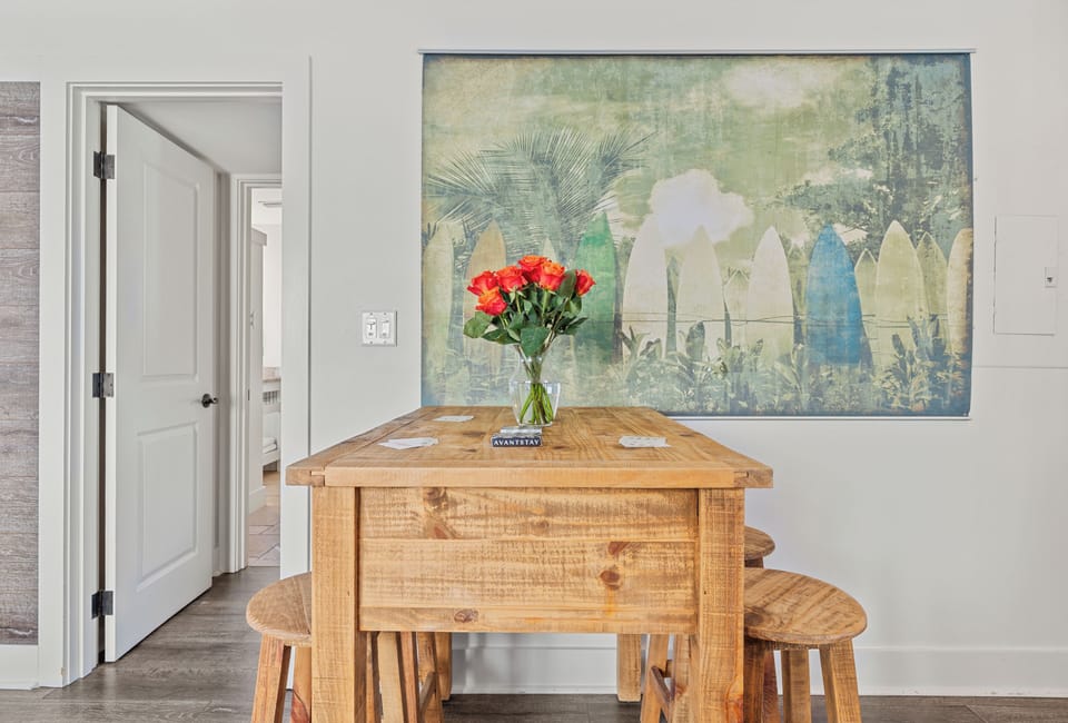 Cozy kitchen dining area with an oak table, stools, and vibrant surfboard-themed artwork.