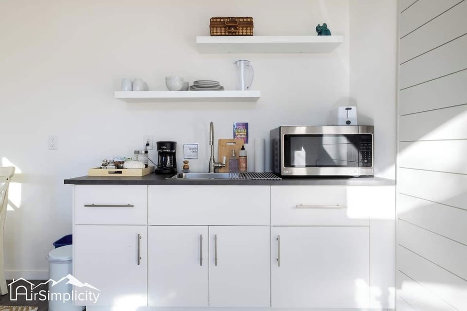 - Bright, modern kitchenette with everything you need for a cozy, convenient stay
- Features include a microwave, coffee station, open shelving, and stainless steel sink
- Organized and minimalist design keeps the space functional and welcoming

