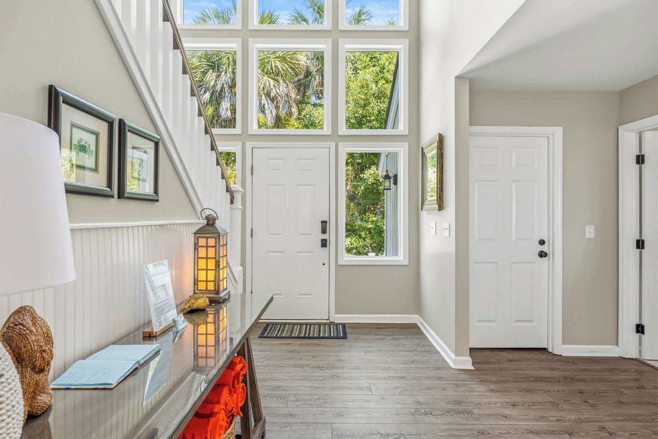 Floor to ceiling windows frame the lush greenery outside, washing this airy entryway in a soft morning glow. Natural wood floors and shiplap accents create a calm, tactile greeting for every guest who walks through the door.
