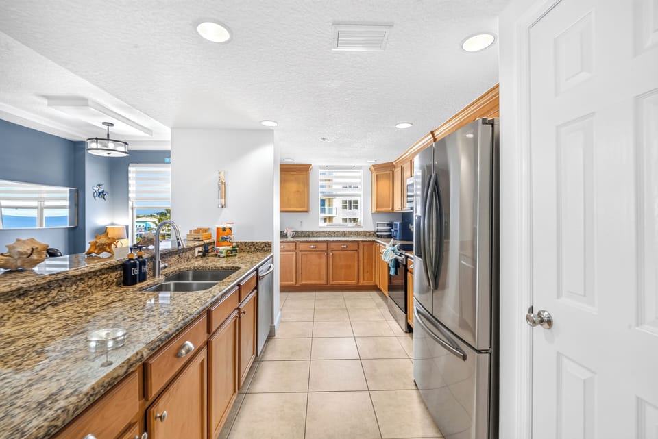 Your fully equipped kitchen awaits, featuring granite countertops, stainless steel appliances, and everything you need to prepare delicious meals during your stay. Ocean views peek through the window, making cooking here a true pleasure.