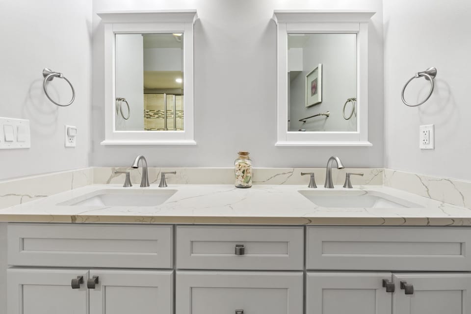 Elegant master bathroom with dual sinks, quartz countertops, modern fixtures, and bright mirrors for a spa-like retreat.